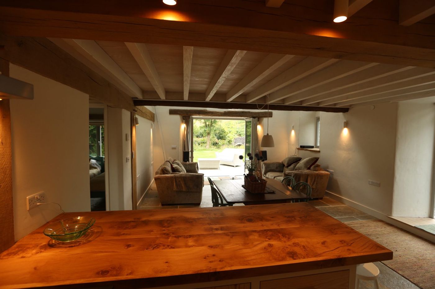 The open-plan kitchen and living room, oak worktop in the foreground and the garden through the doors