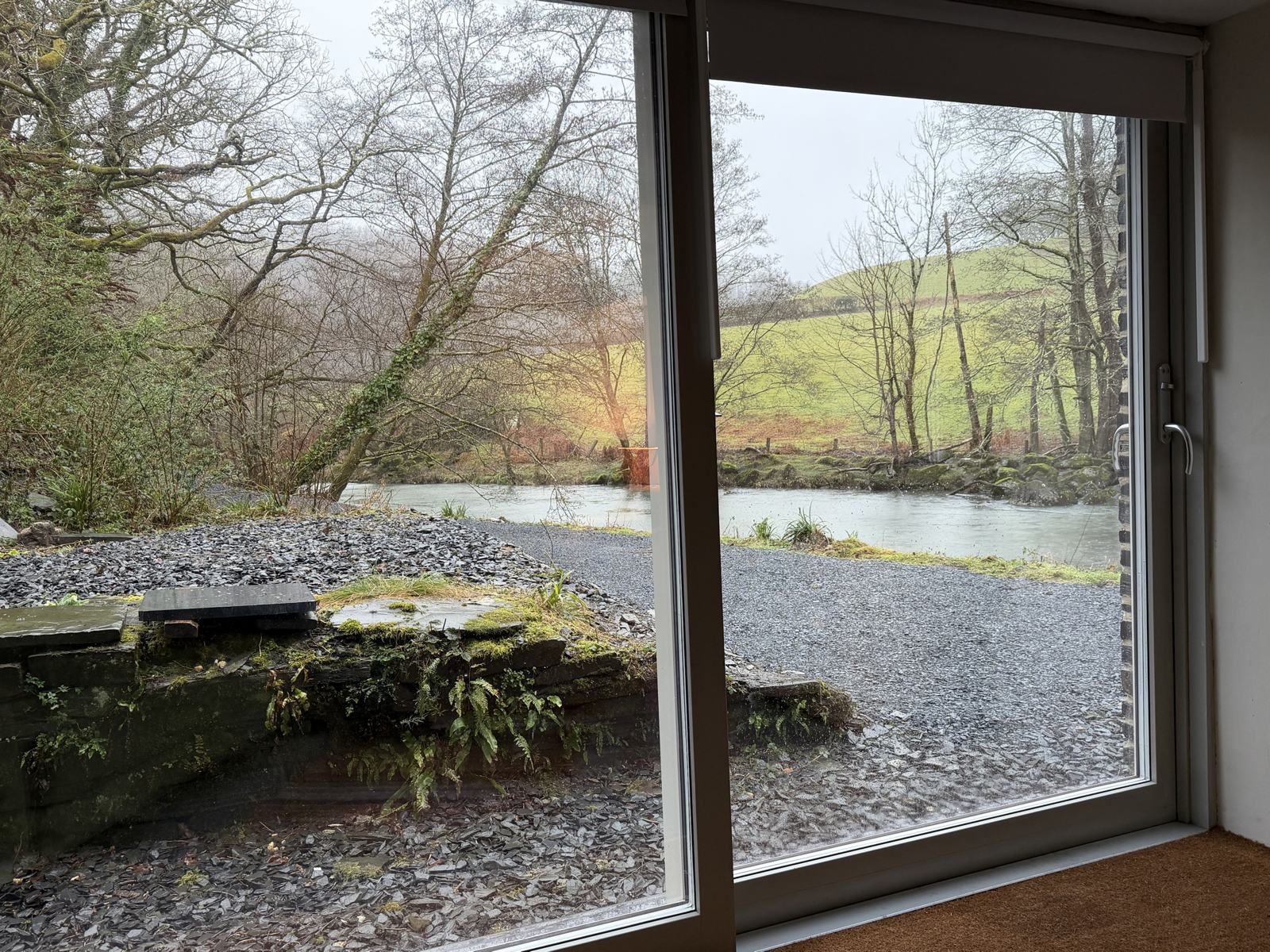 The river through the Mill's window on a grey winter day, the field green beyond